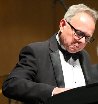 A person in a tuxedo and glasses  Description automatically generated